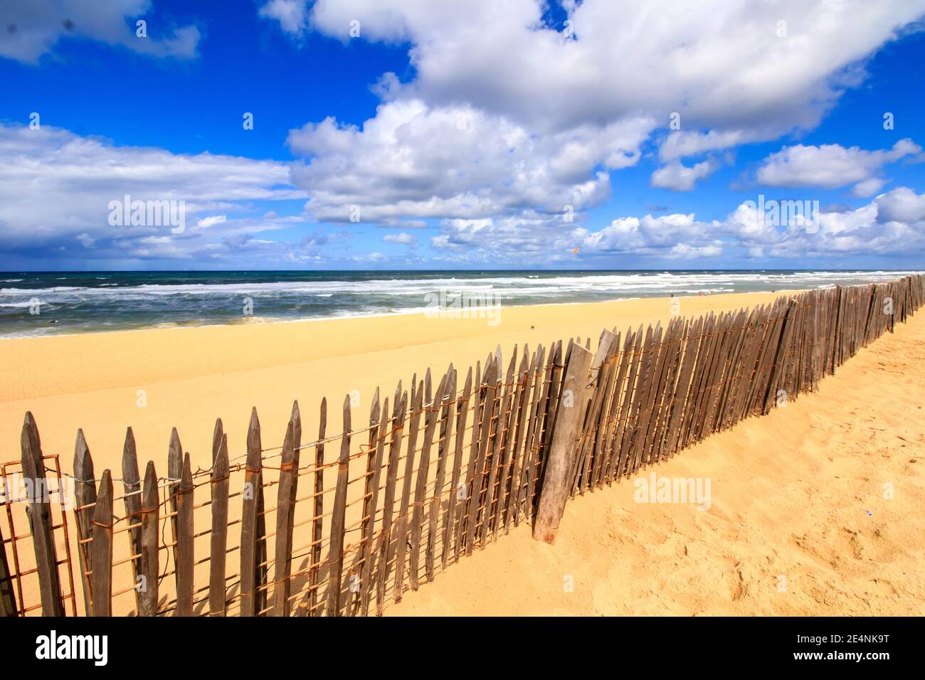 Bellissima spiaggia di sabbia sul lato della costa atlantica francese. Giornata estiva soleggiata con cielo blu e nuvole bianche e tradizionale barriera in legno. Foto Stock