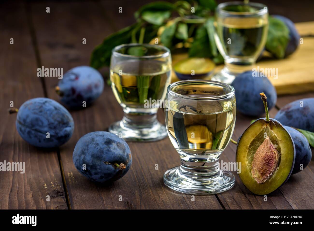 Brandy di prugne o schnapps in bicchieri e prugne fresche gustose su un tavolo di legno. Messa a fuoco selettiva. Foto Stock