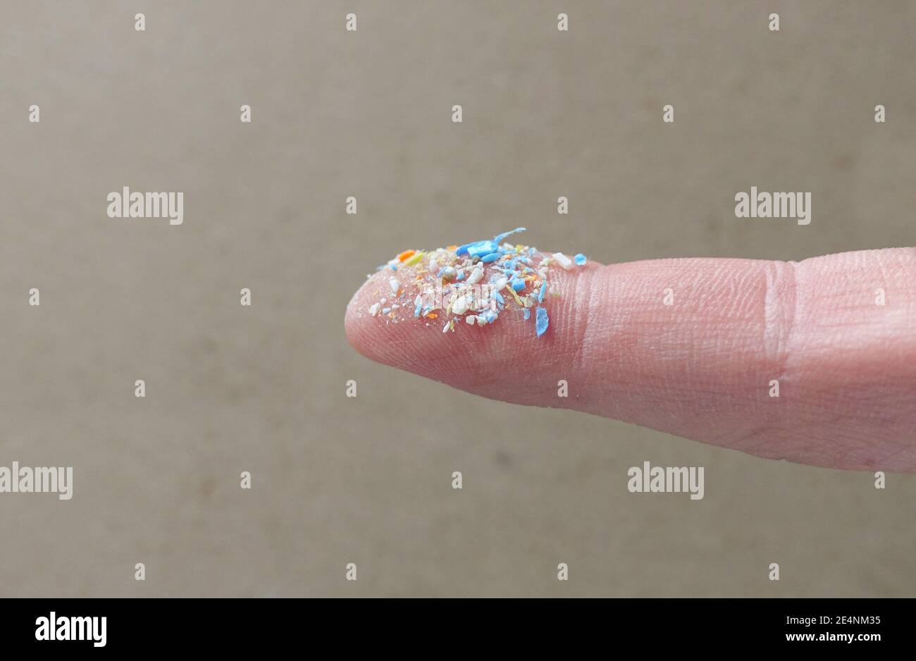 Primo piano della foto laterale delle microplastiche su un dito umano. Concetto creativo di inquinamento idrico e riscaldamento globale. Idea del cambiamento climatico. Un mazzo di plastica Foto Stock