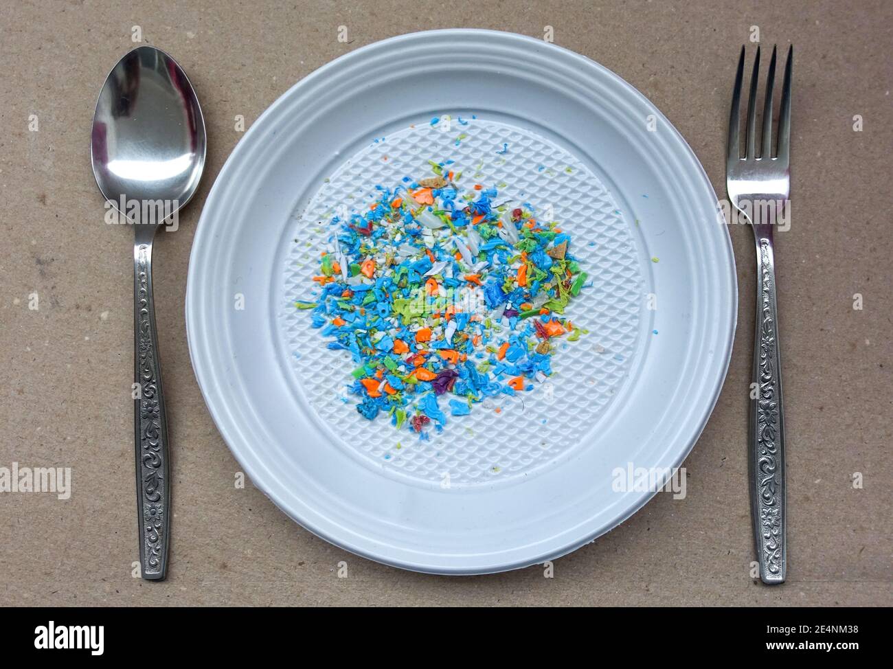 Vista ad alto angolo di microplastica su una piastra monouso con forcella e cucchiaio sulla parte superiore. Concetto di inquinamento idrico e riscaldamento globale. Cambiamento climatico. Foto Stock