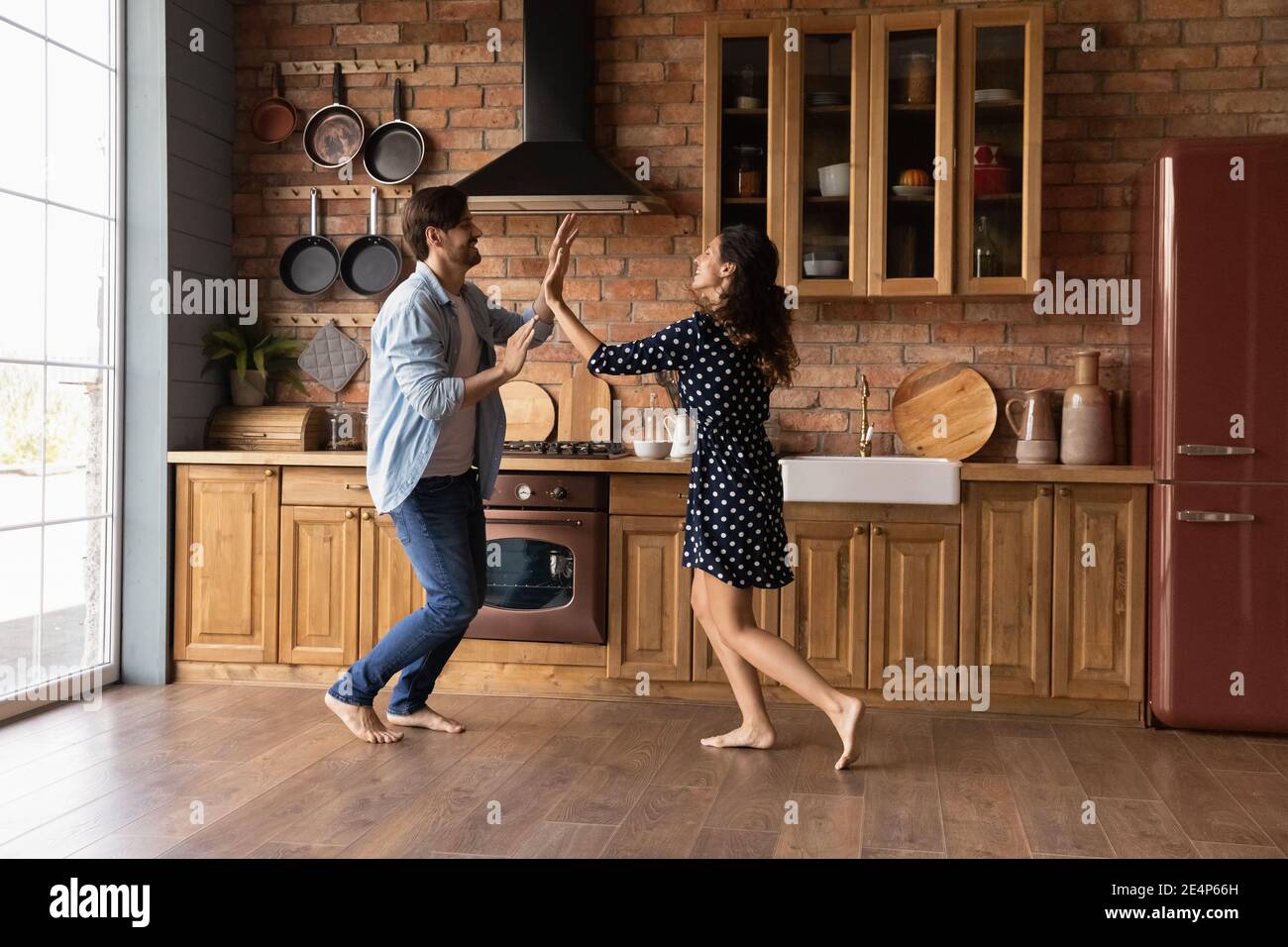 Le coppie felici si divertono a ballare insieme nella cucina moderna Foto Stock