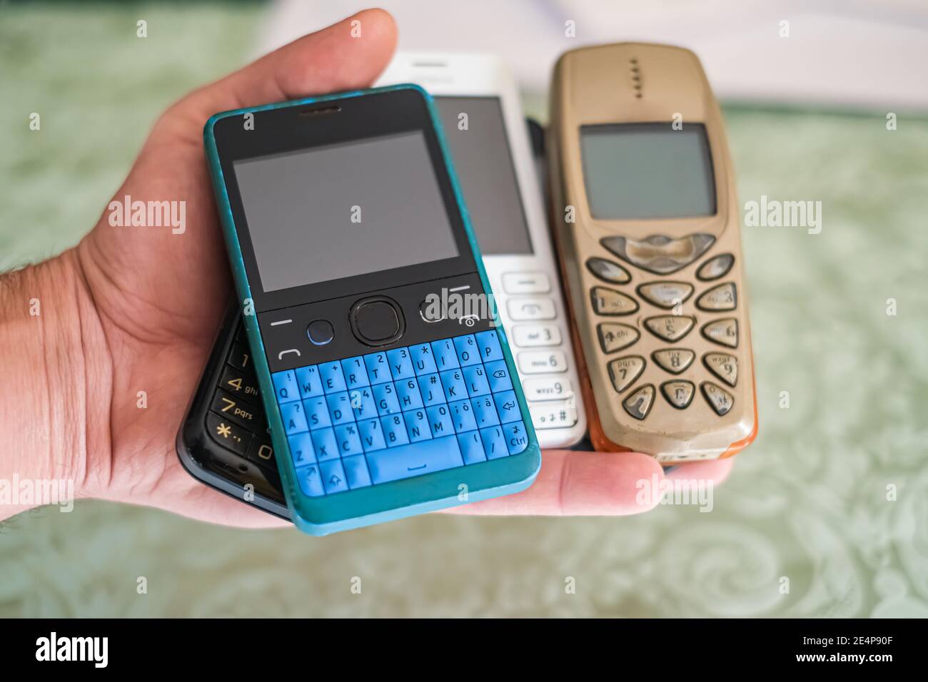 Mano dell'uomo mentre tiene il mucchio dei telefoni mobili di vecchia generazione, tecnologia concetto Foto Stock
