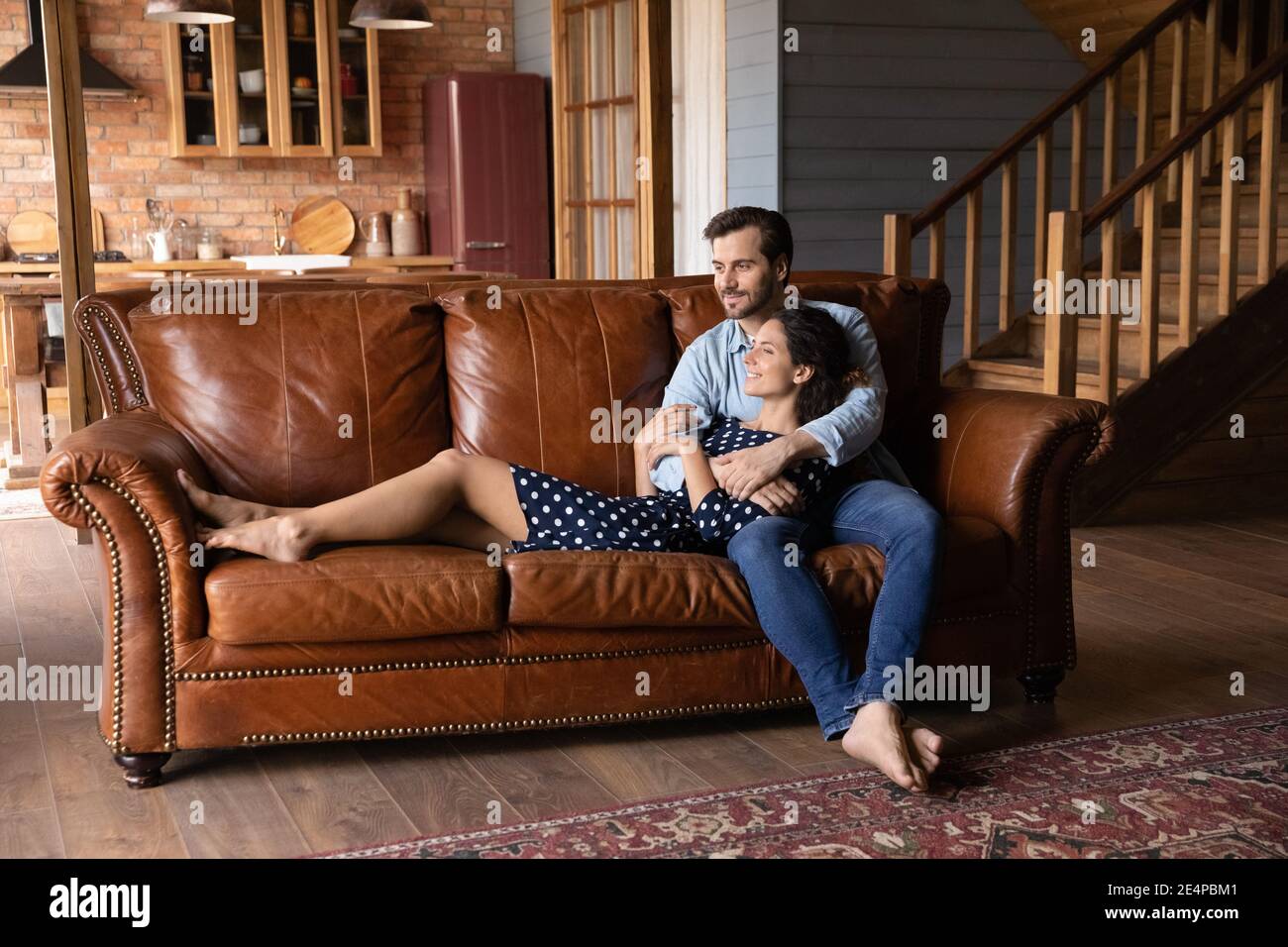 Felice coppia rilassarsi sul divano a casa abbracciando sognare Foto Stock