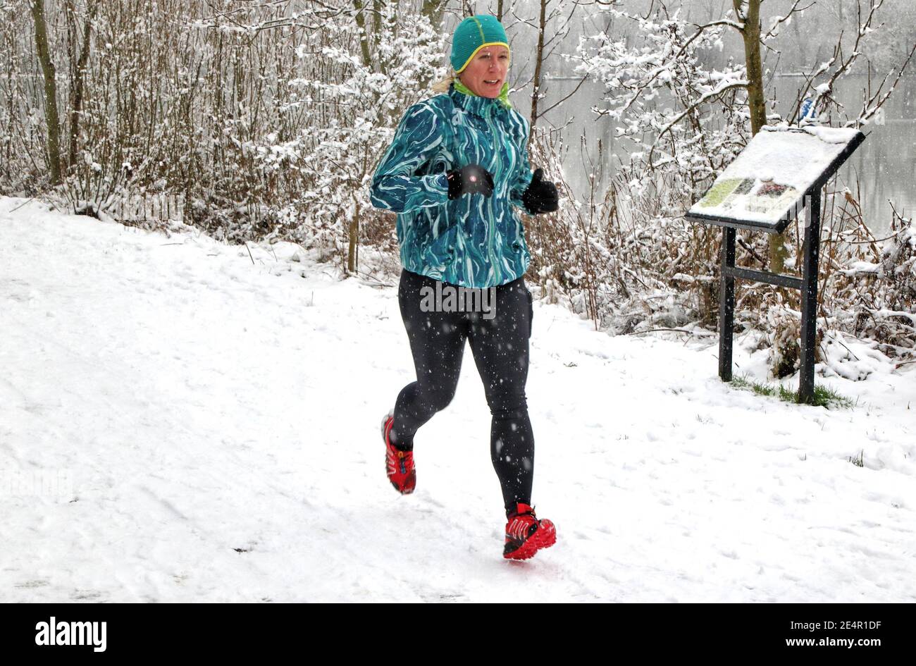 Una donna che fa jogging durante la nevicata.con gravi avvertimenti meteorologici emessi in tutto il Regno Unito, compreso il sud e l'est del paese. Bedford ha avuto la sua prima nevicata significativa in diversi anni. Dopo la neve a pranzo, improvvisamente gli innevatori si sono arenati in tutto gli spazi verdi coperti di neve. Foto Stock