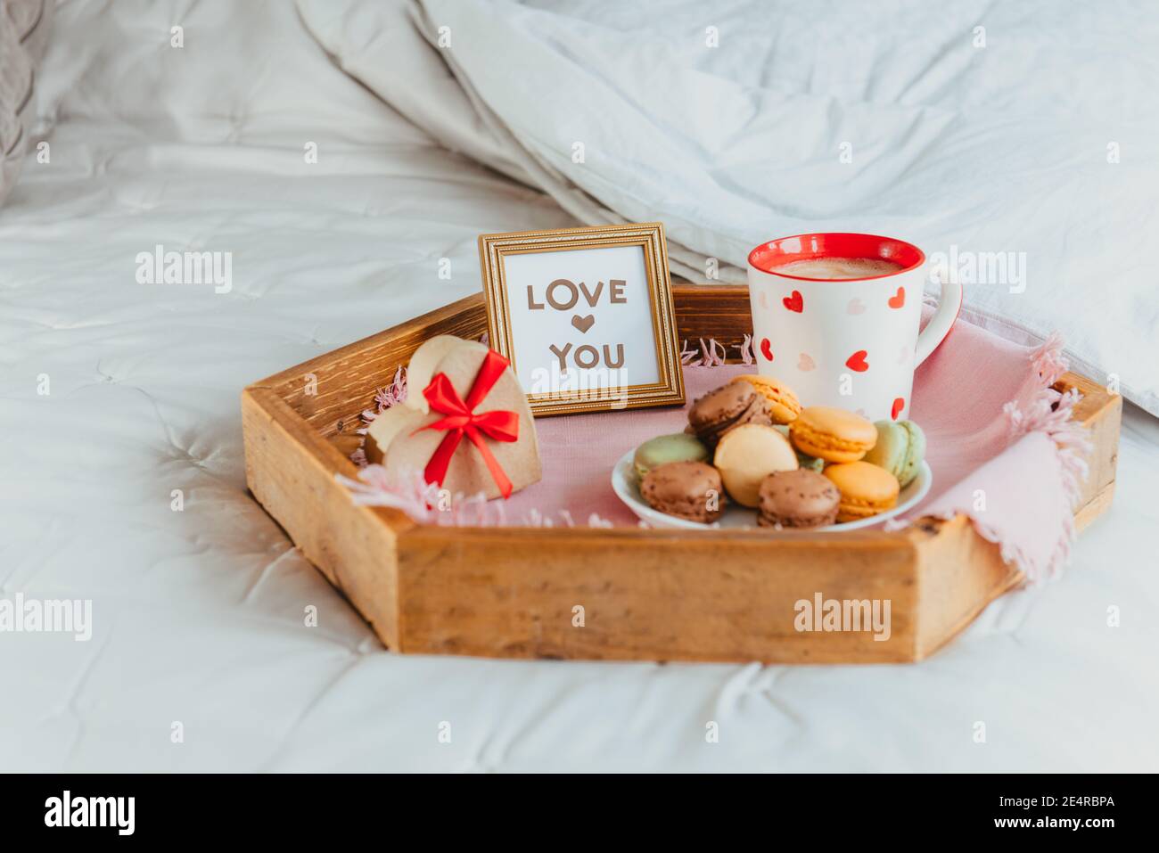 Colazione di San Valentino a letto per amante. Carte d'amore nella cornice,  una tazza di caffè o cacao, macaroon, scatola regalo a forma di cuore con  nastro rosso sopra Foto stock -