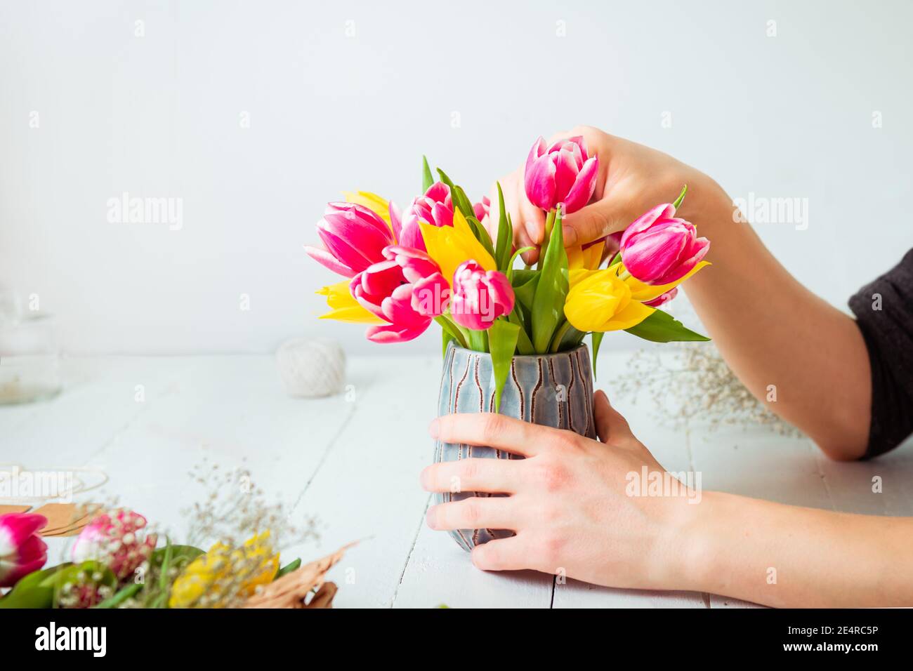 Nessun uomo giovane faccia che fa il bouquet primaverile usando i tulipani. Auto-educazione online di floristry. Imparare la disposizione dei fiori. Consegna fiori. Fiorista maschile Foto Stock
