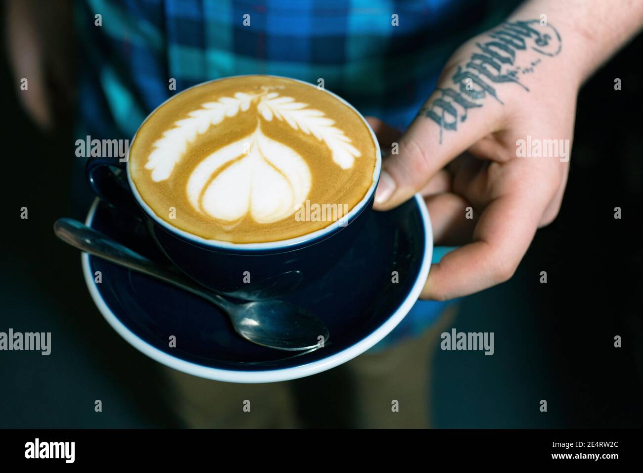 GRAN BRETAGNA / Inghilterra / Londra / mano con tatoo che tiene il caffè Cup in un caffè al coperto a Londra.Close up di mani per tenere una tazza di caffè Foto Stock