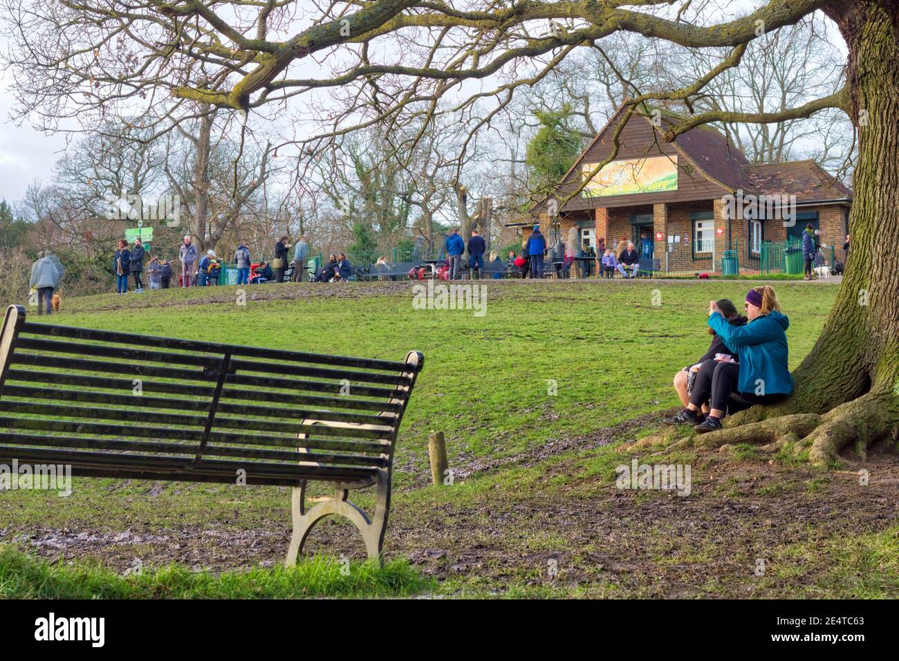 Donna che scatta una foto di bosco fuori bar negozio dove la gente accodata per le bevande calde take away mantenendo la presa sociale, Londra Foto Stock
