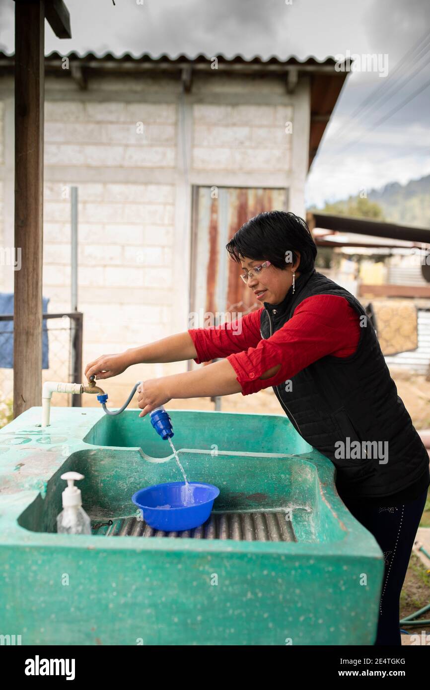 Una donna utilizza un sistema di filtrazione dell'acqua pulita basato sul rubinetto a casa sua a Cantel, Guatemala. Foto Stock