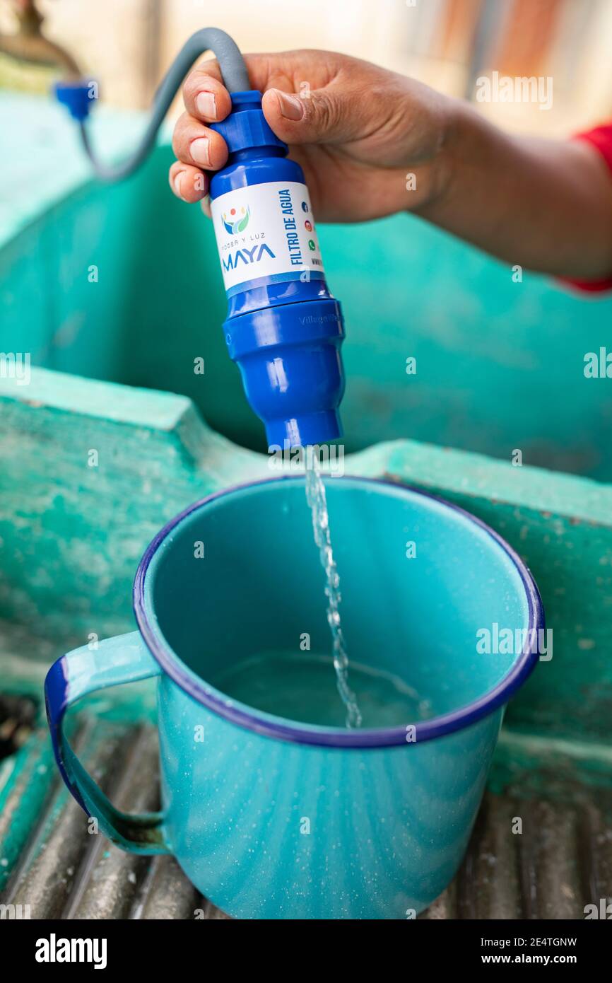 Una donna utilizza un sistema di filtrazione dell'acqua pulita basato sul rubinetto a casa sua a Cantel, Guatemala. Foto Stock