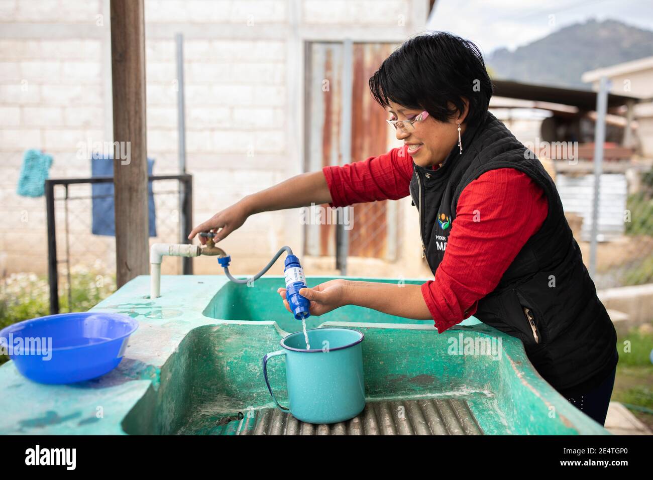 Una donna utilizza un sistema di filtrazione dell'acqua pulita basato sul rubinetto a casa sua a Cantel, Guatemala. Foto Stock
