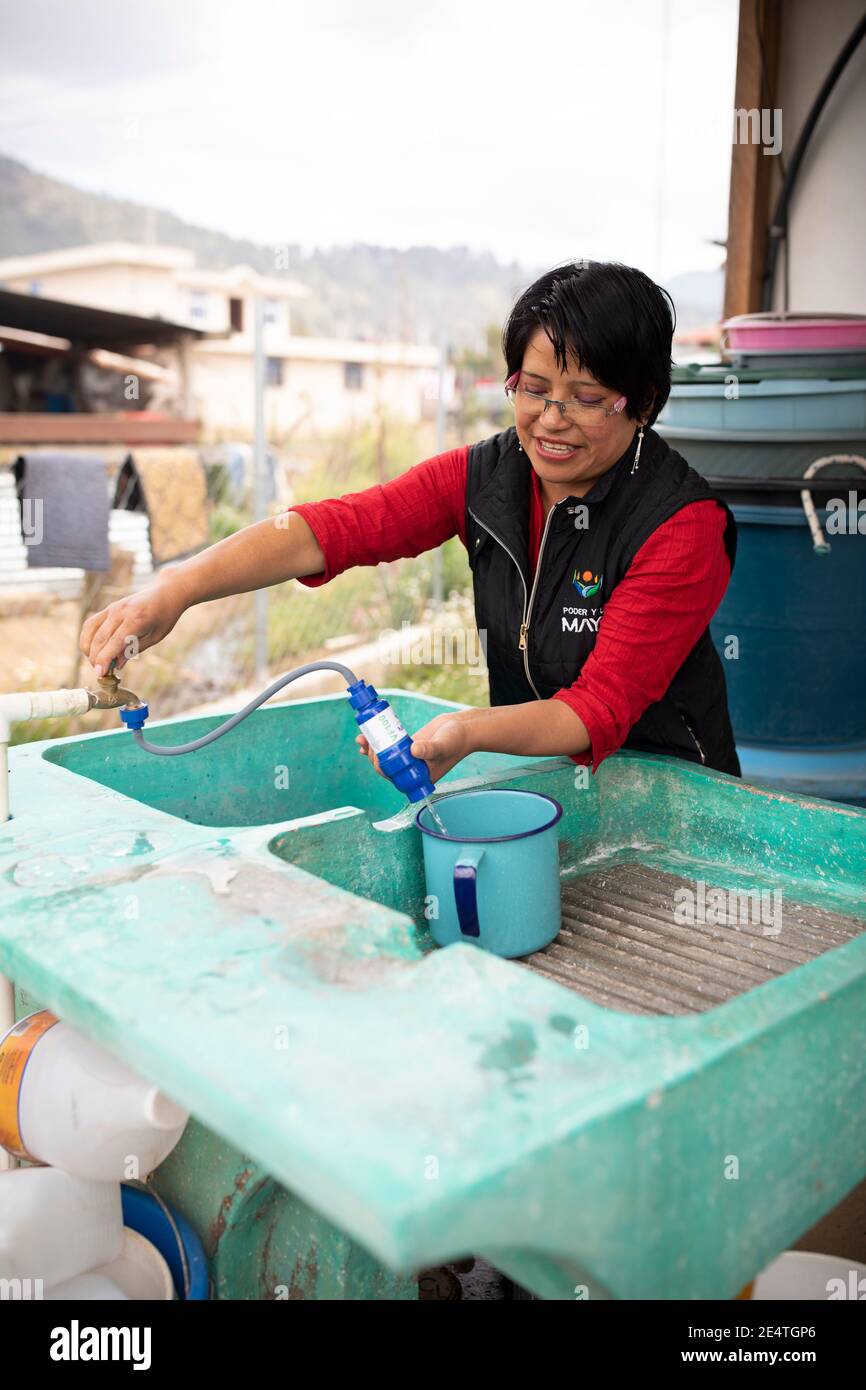 Una donna utilizza un sistema di filtrazione dell'acqua pulita basato sul rubinetto a casa sua a Cantel, Guatemala. Foto Stock