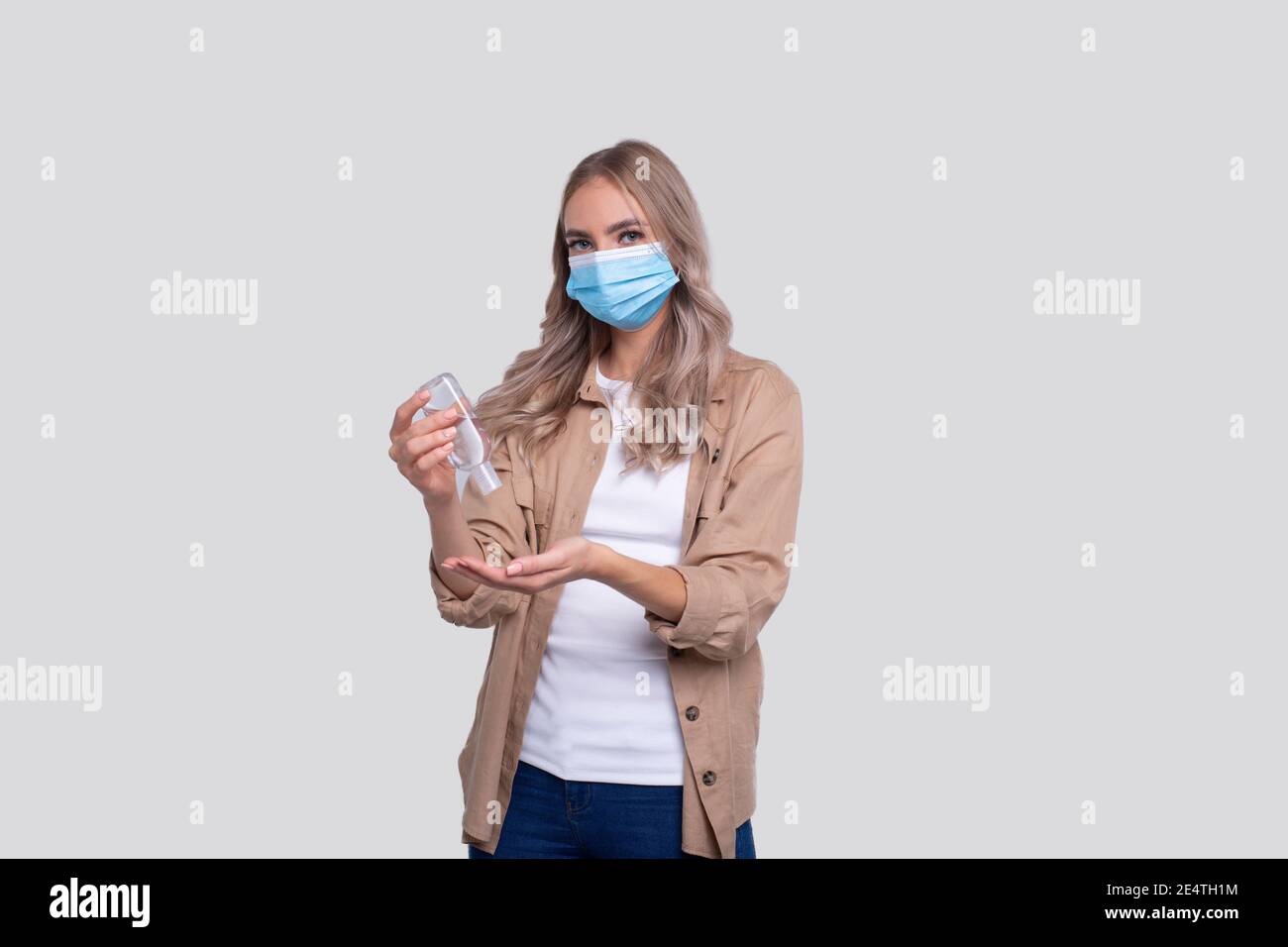 Ragazza che indossa una maschera medica con igienizzatore per le mani. Ragazza usando le mani antisettico isolato Foto Stock