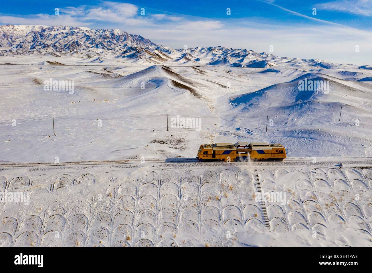 Pechino, Cina. 21 Gennaio 2021. La foto aerea scattata il 21 gennaio 2021 mostra una macchina per la rimozione della neve su un binario ferroviario in funzione nella zona ventosa di Maytas lungo la ferrovia Karamay-Tacheng, nella regione autonoma di Xinjiang Uygur, nella Cina nord-occidentale. Maytas, soprannominato "Inferno del vento", è un'area selvaggia attraverso la linea ferroviaria Karamay-Tacheng a Xinjiang. È anche un luogo in cui il team di riparazione Tiechanggou sotto la China Railway Urumqi Bureau Group Co., Ltd. È sull'orologio 24 ore al giorno per garantire il funzionamento sicuro di tutti i treni che passano. Credit: HU Huhu/Xinhua/Alamy Live News Foto Stock