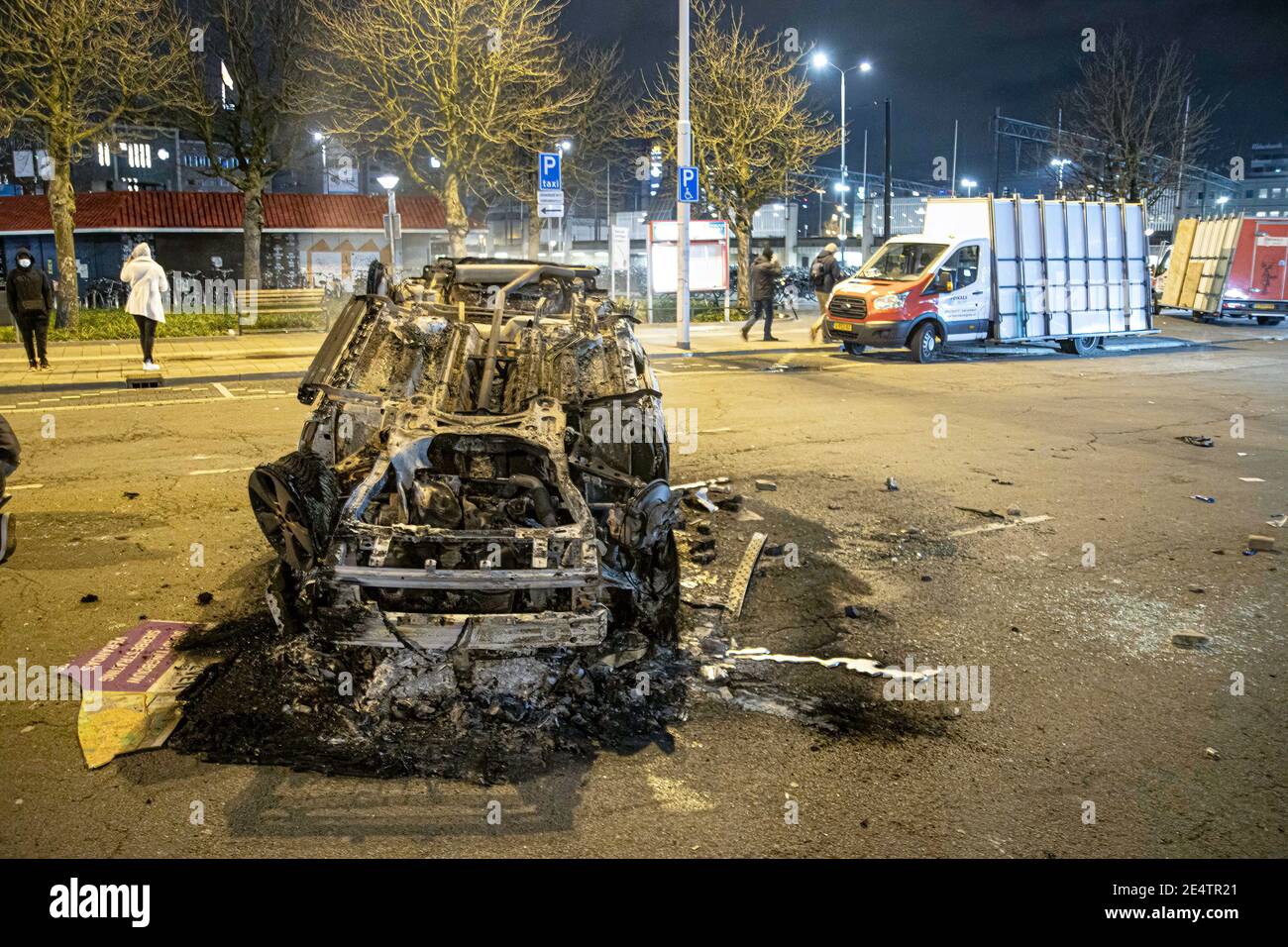 Dopo la dimostrazione, un'auto del ProRail è bruciata di fronte alla stazione ferroviaria centrale di Eindhoven. Detriti sulle strade di Eindhoven, il seguito di una manifestazione contro il nuovo Coronavirus Covid19 misure di copertura dopo il blocco. Gli scontri tra i manifestanti e gli agenti di polizia hanno portato alla combustione di un'auto, alla rottura delle finestre, al lancio di pietre e alla messa a punto di blocchi stradali con biciclette in fiamme, mentre la stazione ferroviaria centrale è stata danneggiata. La polizia ha fatto 55 arresti. Il coprifuoco è stato imposto tra le 21:00 e le 04:30 ora locale. Foto Stock
