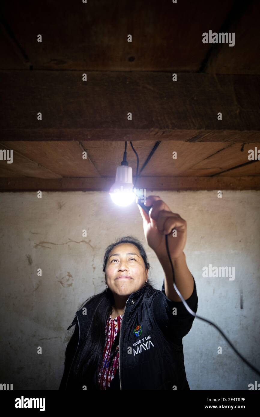 Un tecnico della società locale di energia senza scopo di lucro prova un nuovo sistema di illuminazione a energia solare in una casa a Cantel, Guatemala, Centr Foto Stock