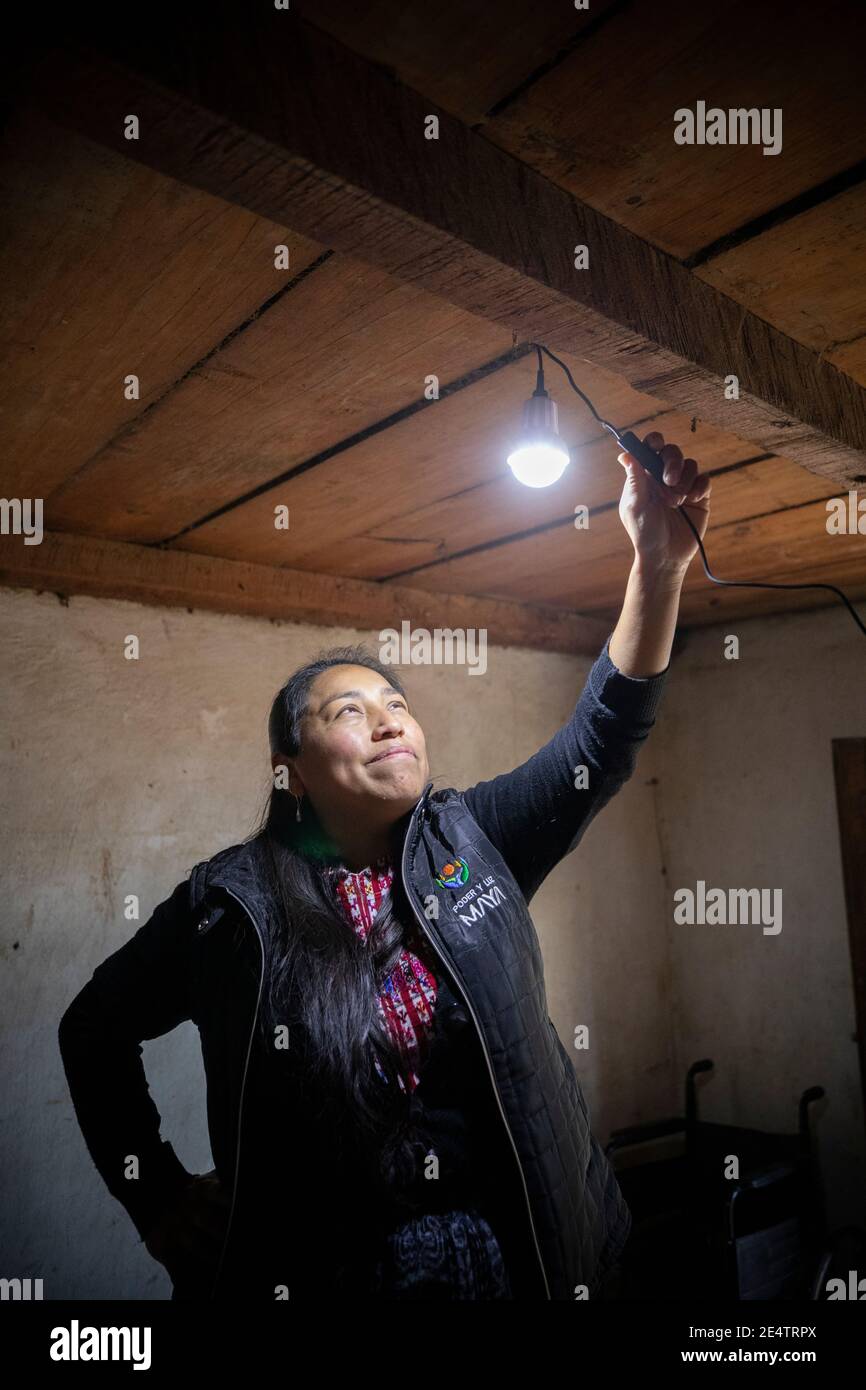 Un tecnico della società locale di energia senza scopo di lucro prova un nuovo sistema di illuminazione a energia solare in una casa a Cantel, Guatemala, Centr Foto Stock