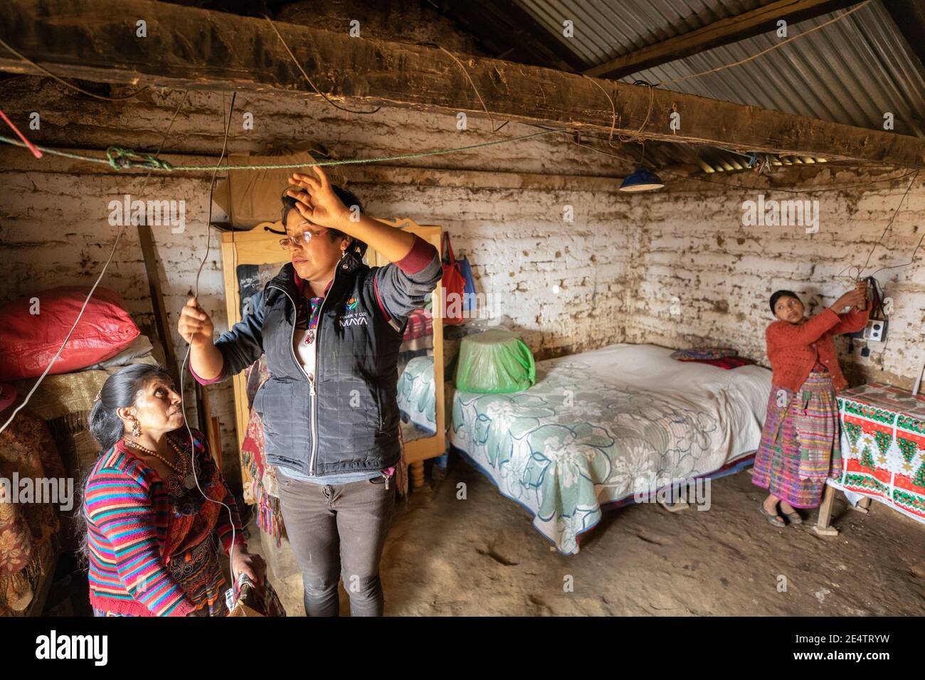 Un tecnico della società locale di energia senza scopo di lucro installa un nuovo sistema di illuminazione a energia solare in una casa a Cantel, Guatemala. Foto Stock