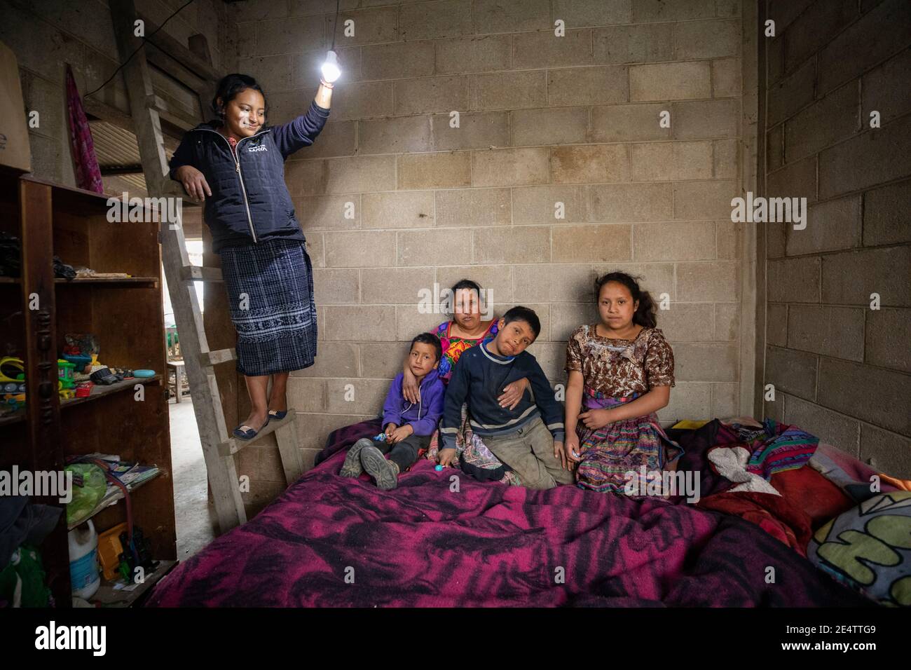 Un tecnico della società locale di energia senza scopo di lucro prova un nuovo sistema di illuminazione a energia solare in una casa a Cantel, Guatemala, America Centrale. Foto Stock