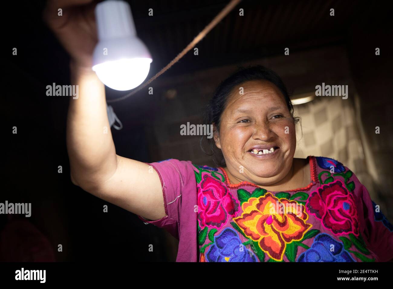 Una donna accende per la prima volta le sue luci a energia solare a casa sua a Cantel, Guatemala, America Centrale. Foto Stock