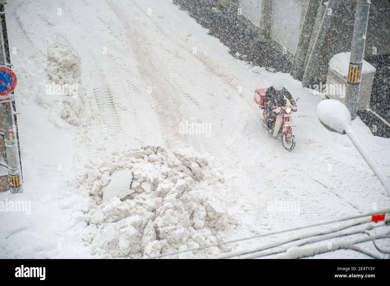 Un postino giapponese su una moto che attraversa una tempesta di neve. Foto Stock