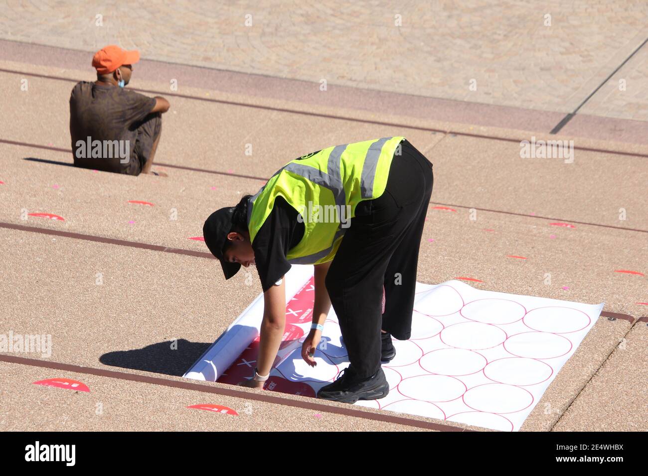 Sydney, Australia. 25 gennaio 2021. Il palcoscenico e la recinzione circostante sono stati eretti prima delle celebrazioni del giorno dell'Australia nell'area del piazzale dell'Opera House di Sydney. Nella foto: Un operaio mette degli adesivi sui gradini dell'Opera House di Sydney indicando dove sedersi e dove non sedersi per assistere l'allontanamento sociale. Credit: Carota/Alamy Live News Foto Stock