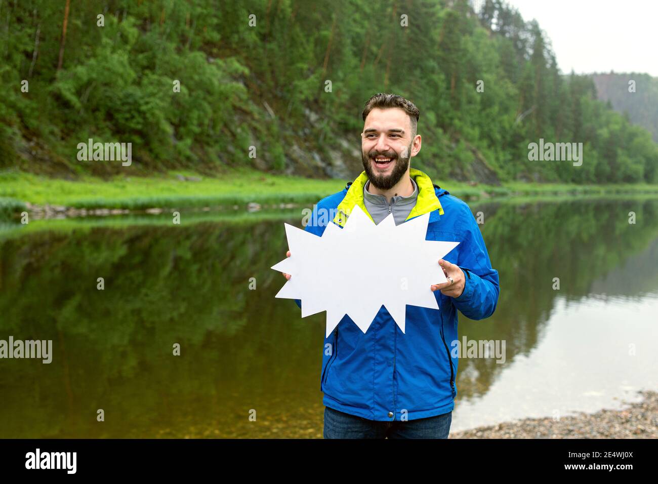 Sorridente giovane uomo che tiene banner o messaggio bolla sulla natura sfondo Foto Stock
