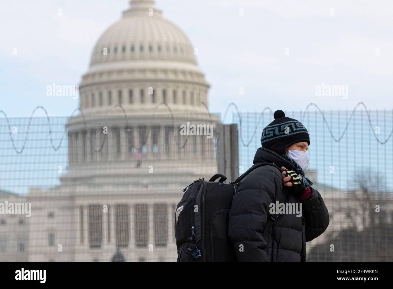 Washington, Stati Uniti. 25 Gennaio 2021. Un uomo che indossa una maschera cammina oltre l'edificio del Campidoglio degli Stati Uniti a Washington, DC, Stati Uniti, 24 gennaio 2021. Il numero totale di casi COVID-19 negli Stati Uniti ha raggiunto 25 milioni la domenica, secondo il Center for Systems Science and Engineering (CSSE) della Johns Hopkins University. Il numero di casi COVID-19 negli Stati Uniti è salito a 25,003,695, con un totale di 417,538 decessi, alle 10:22 ora locale (1522 GMT), secondo il CSSE Tount. Credit: Aaron Schwartz/Xinhua/Alamy Live News Foto Stock