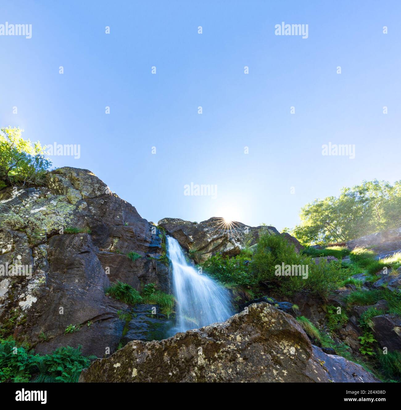Vista dal basso lunga esposizione di cascata e sunstar Foto Stock