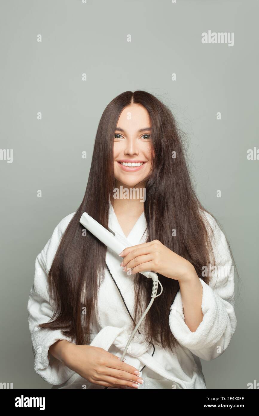 Donna felice raddrizza i capelli su sfondo bianco. Concetto di cura dei capelli Foto Stock