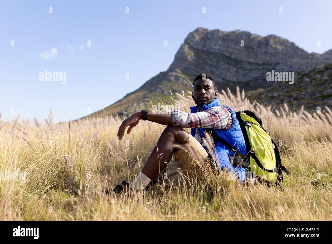 Fit afrcan americano uomo che indossa zaino seduto in campagna di montagna Foto Stock