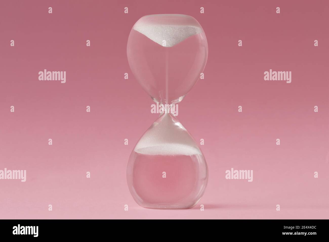 Clessidra capovolta su sfondo rosa - concetto di tempo inverso Foto Stock
