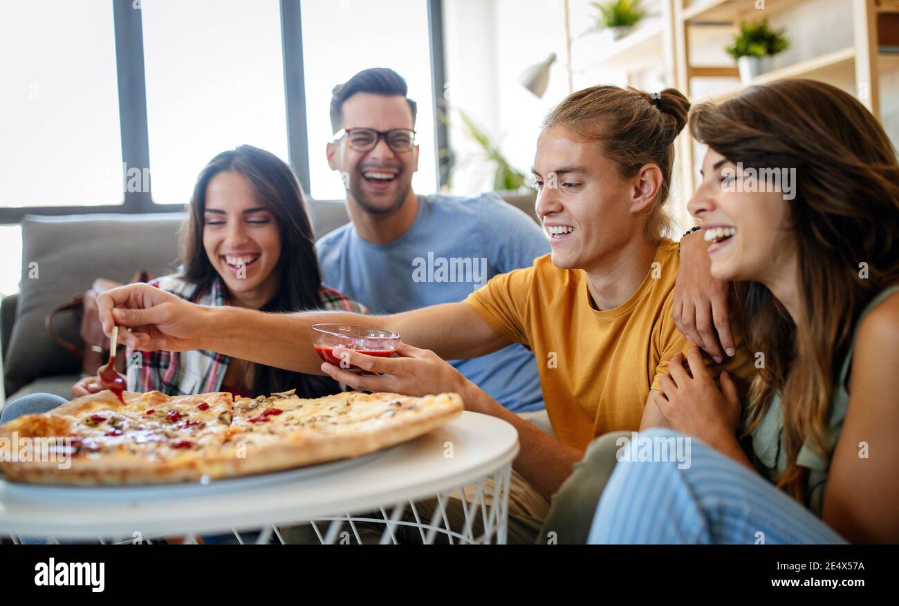 Trascorrere del tempo con gli amici. Gruppo di giovani allegri che parlano e mangiano insieme la pizza Foto Stock