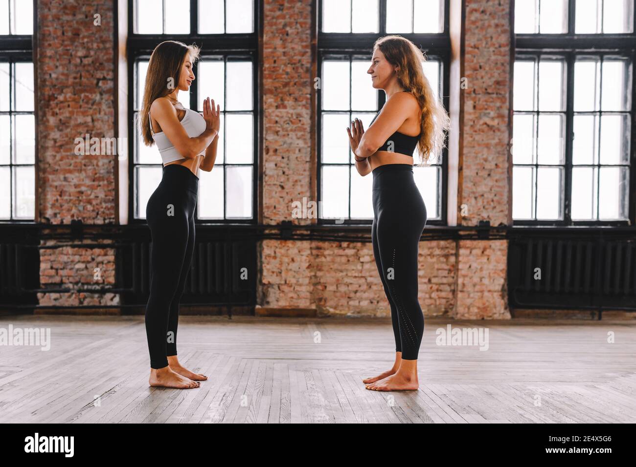 Due giovani femmine fanno complesso di stretching yoga asana in classe stile loft Foto Stock