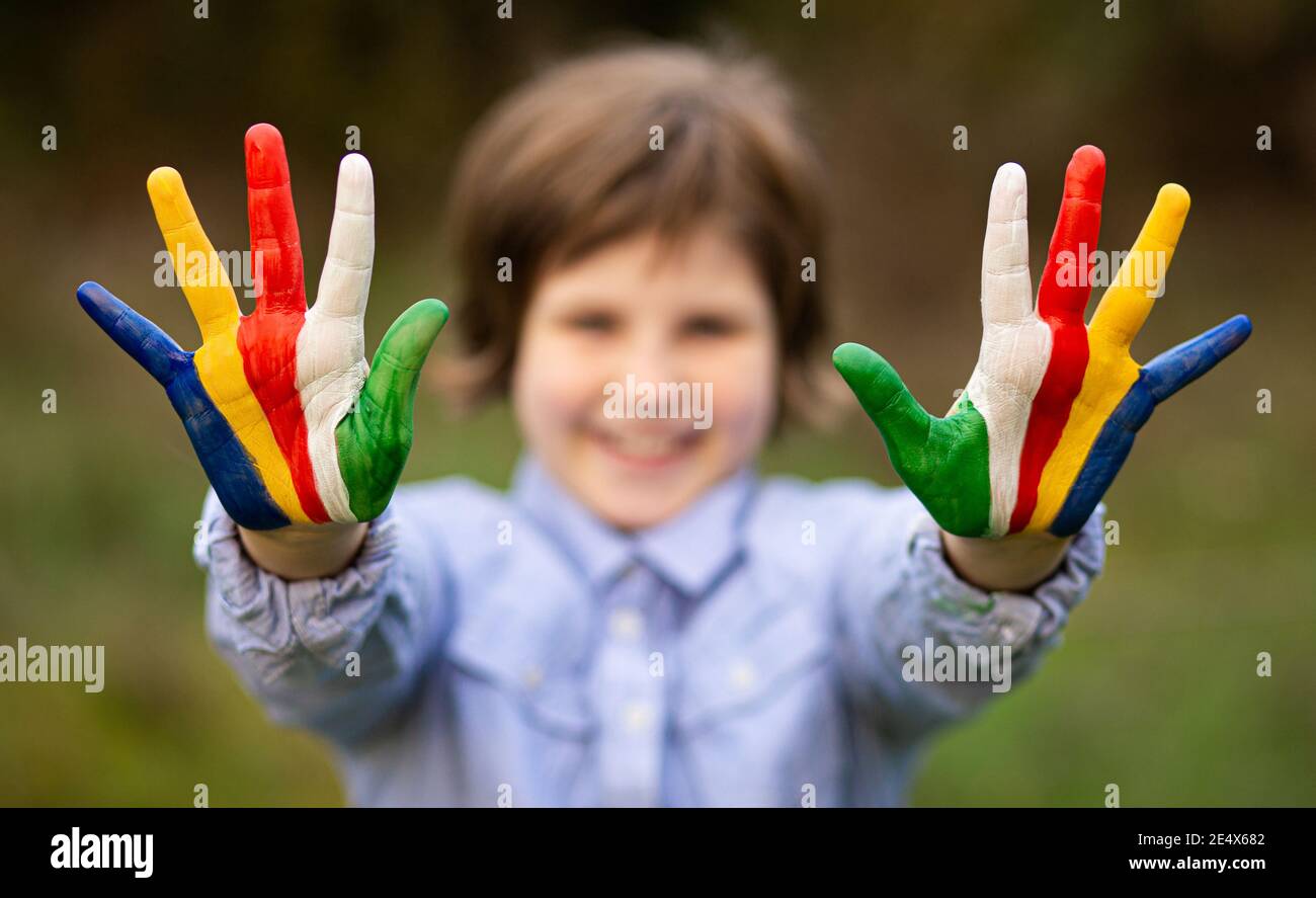 Ritratto esterno di allegra ragazza capretto mostra ciao gesto con mani dipinte in colori bandiera Seychelles. Concentrarsi sulle mani Foto Stock