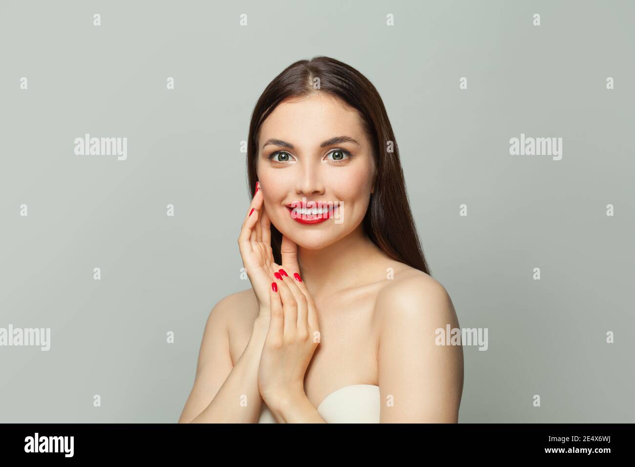 Giovane donna modello brunette con pelle sana e manicure rossa unghie su bianco Foto Stock