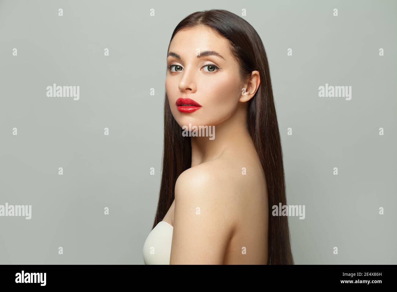 Perfetta Bruna modello moda donna con pelle chiara e lunga capelli lisci sani su sfondo bianco Foto Stock