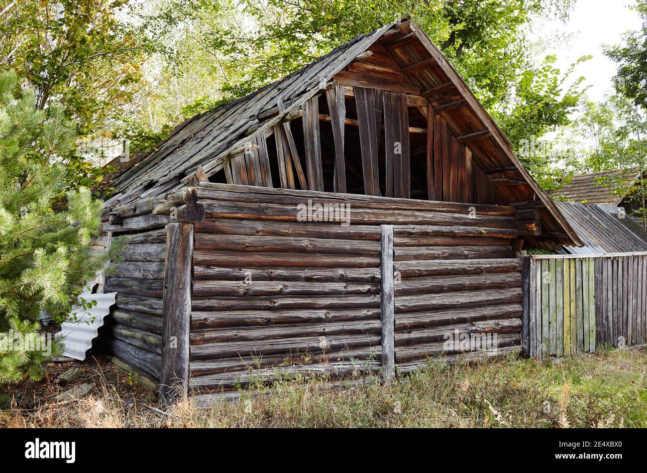 Fienile abbandonato in campagna. Antico edificio in legno con recinzione in autunno Foto Stock
