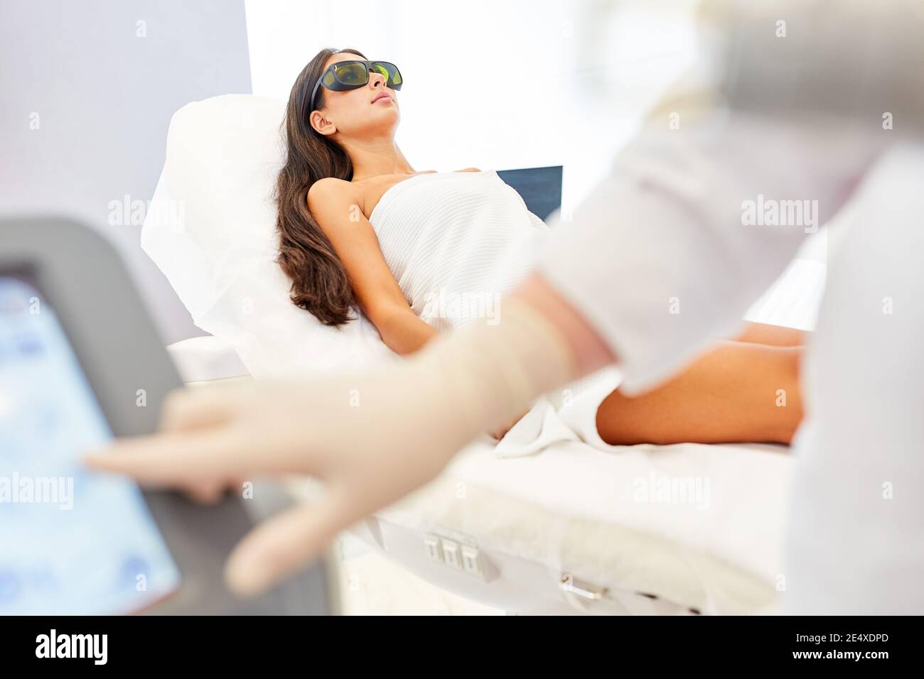 La mano del dermatologo gestisce il monitor per la terapia laser in bellezza clinica Foto Stock