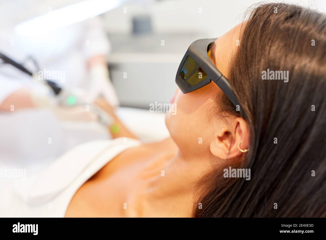 Giovane donna con occhiali protettivi durante la rimozione permanente dei capelli in lo studio cosmetico Foto Stock
