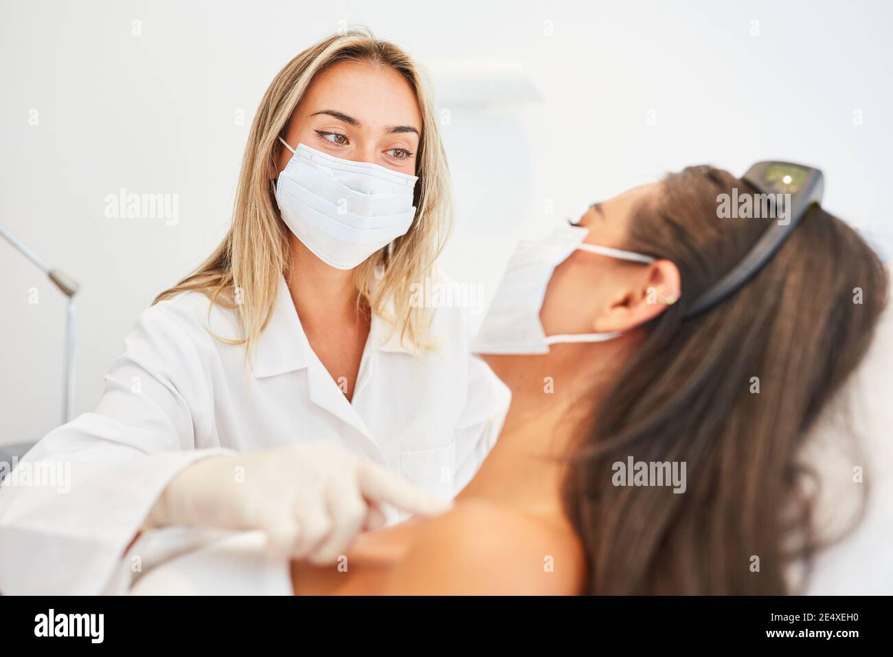 Estetista o dermatologo con maschera facciale durante il trattamento della pelle in lo studio cosmetico Foto Stock