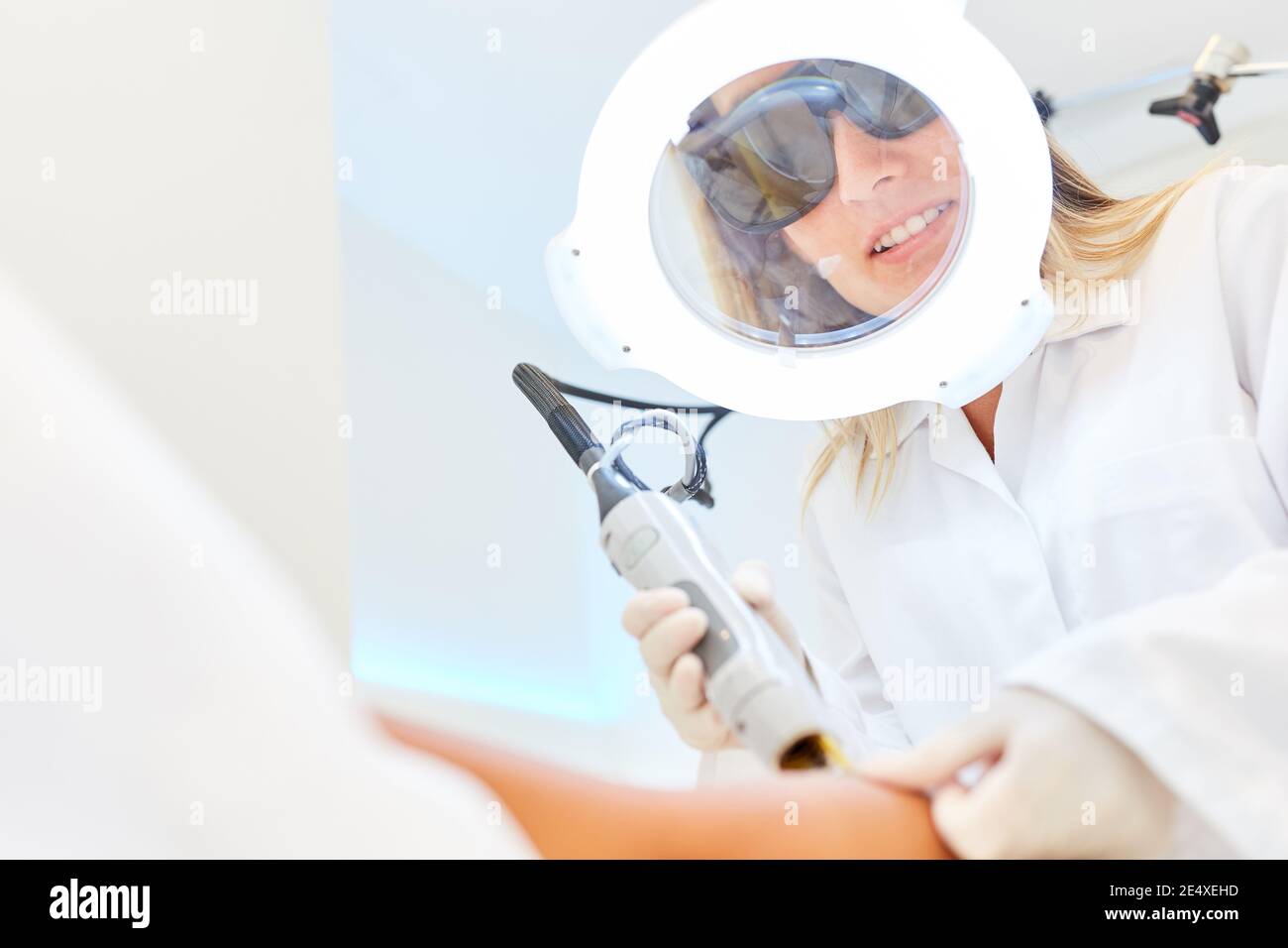 Estetista con lente di ingrandimento durante la rimozione dei capelli con laser alexandrite epilazione Foto Stock