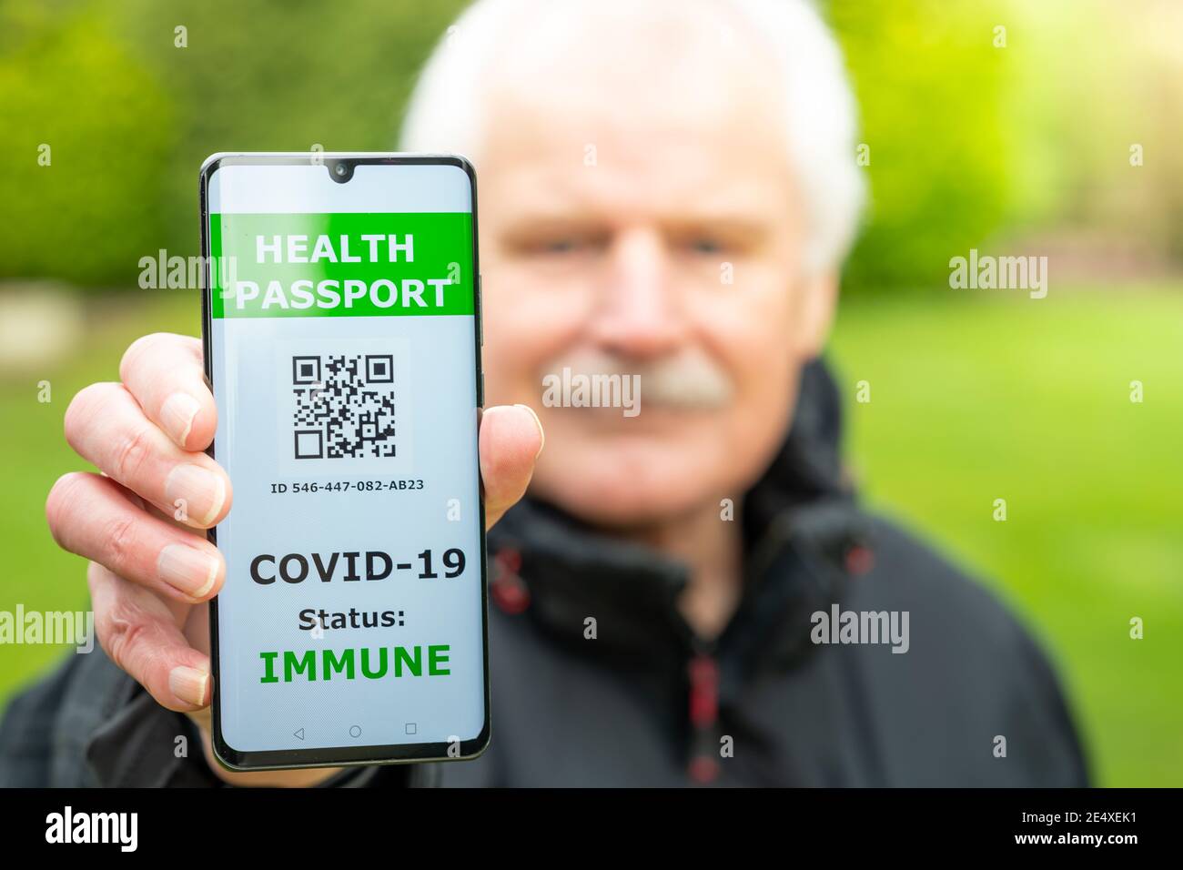 Uomo anziano che mostra un passaporto sanitario su un telefono cellulare, che indica una vaccinazione contro il covid-19. Foto Stock