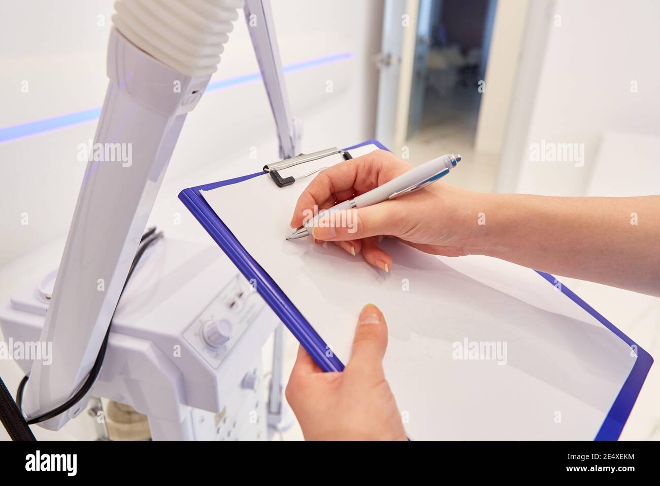 La mano del medico sta facendo note su una clipboard o riempiendo una lista di controllo Foto Stock