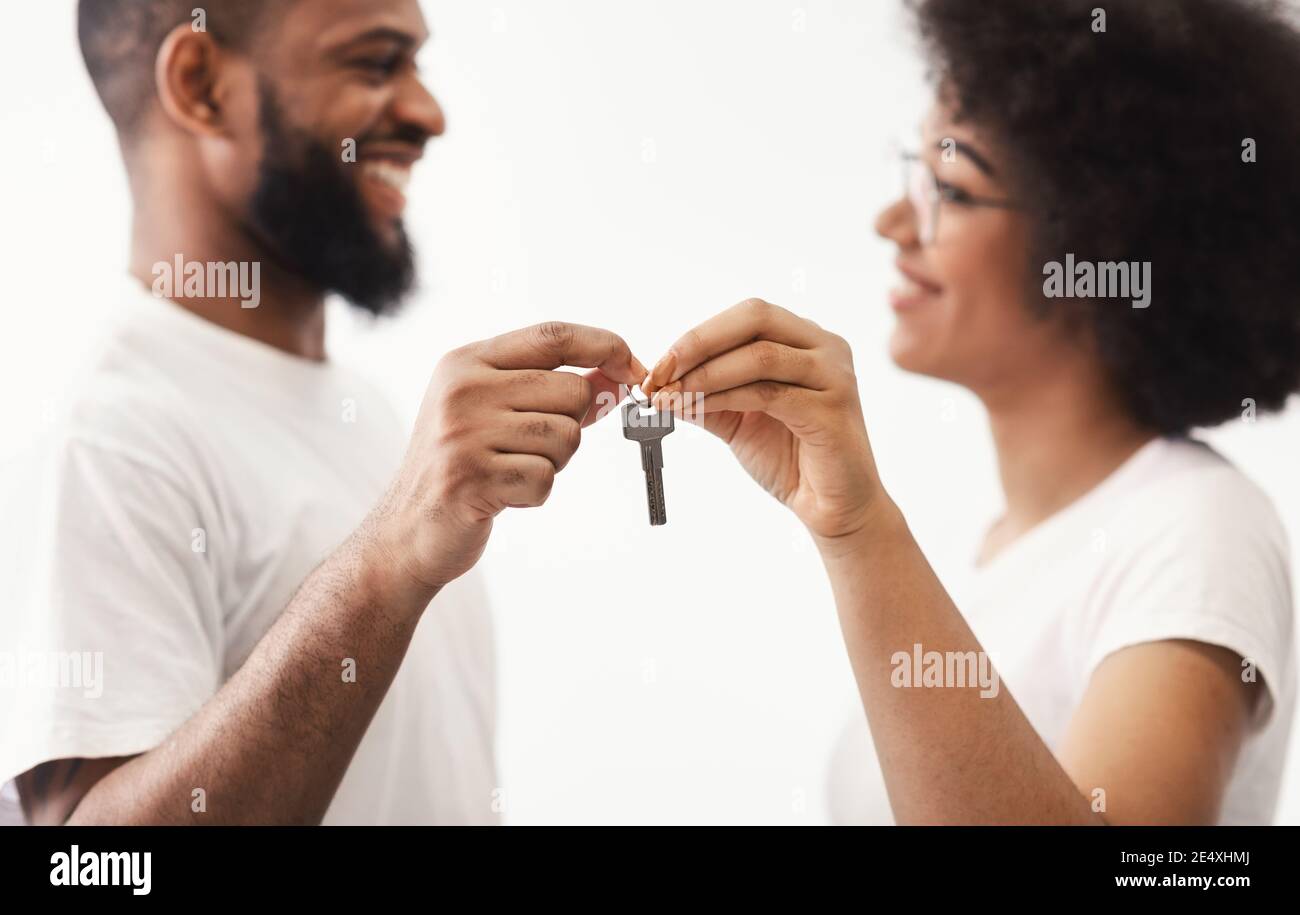 Coppia nera che tiene la nuova chiave della casa che si erifica su sfondo bianco Foto Stock
