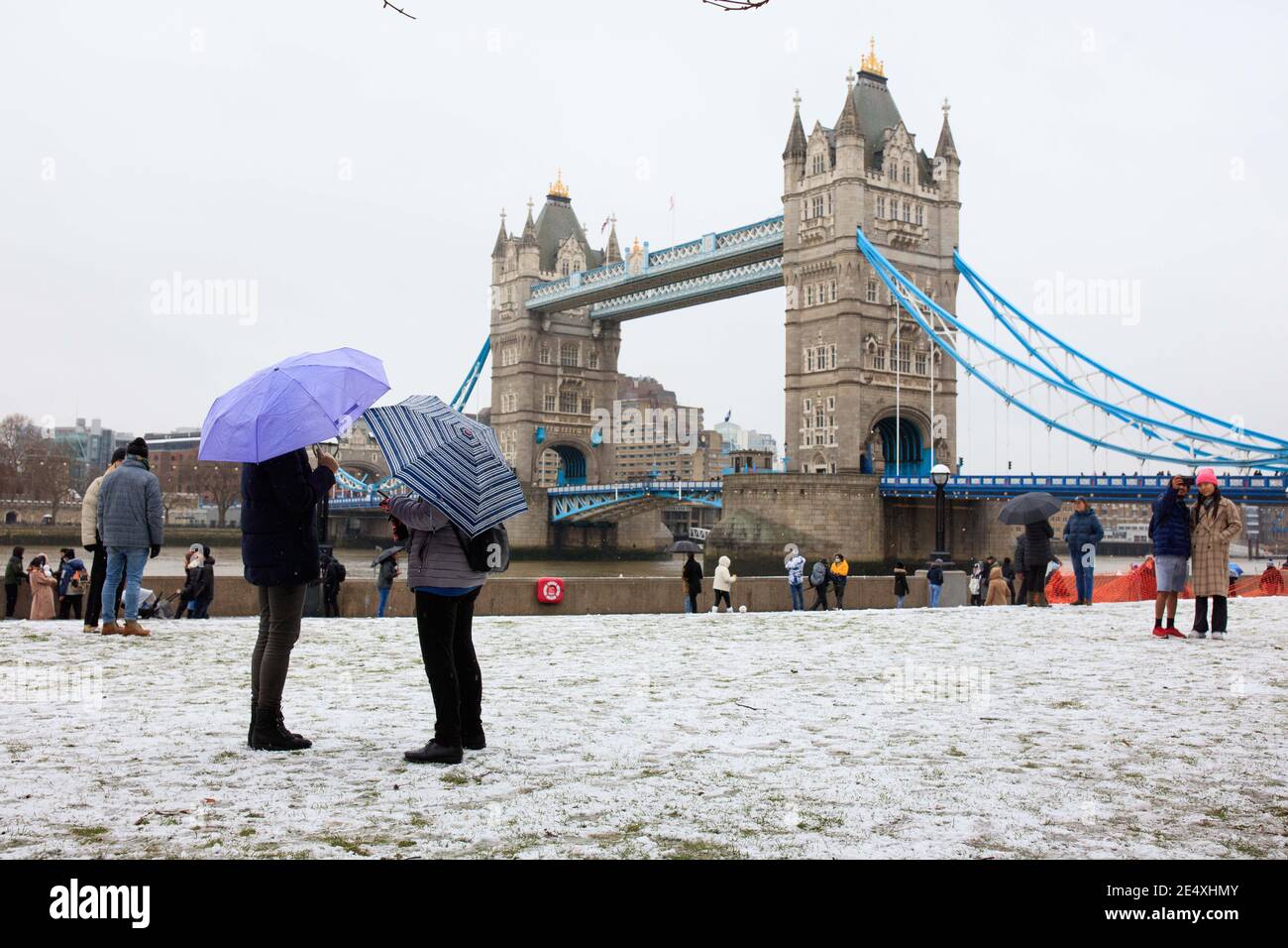 Le persone si fermano a guardare un ponte della Torre innevato a Londra. Foto Stock