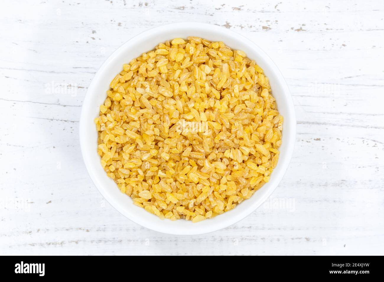 Grani di grano di bulgur da sopra ciotola legno di asse di legno Foto Stock