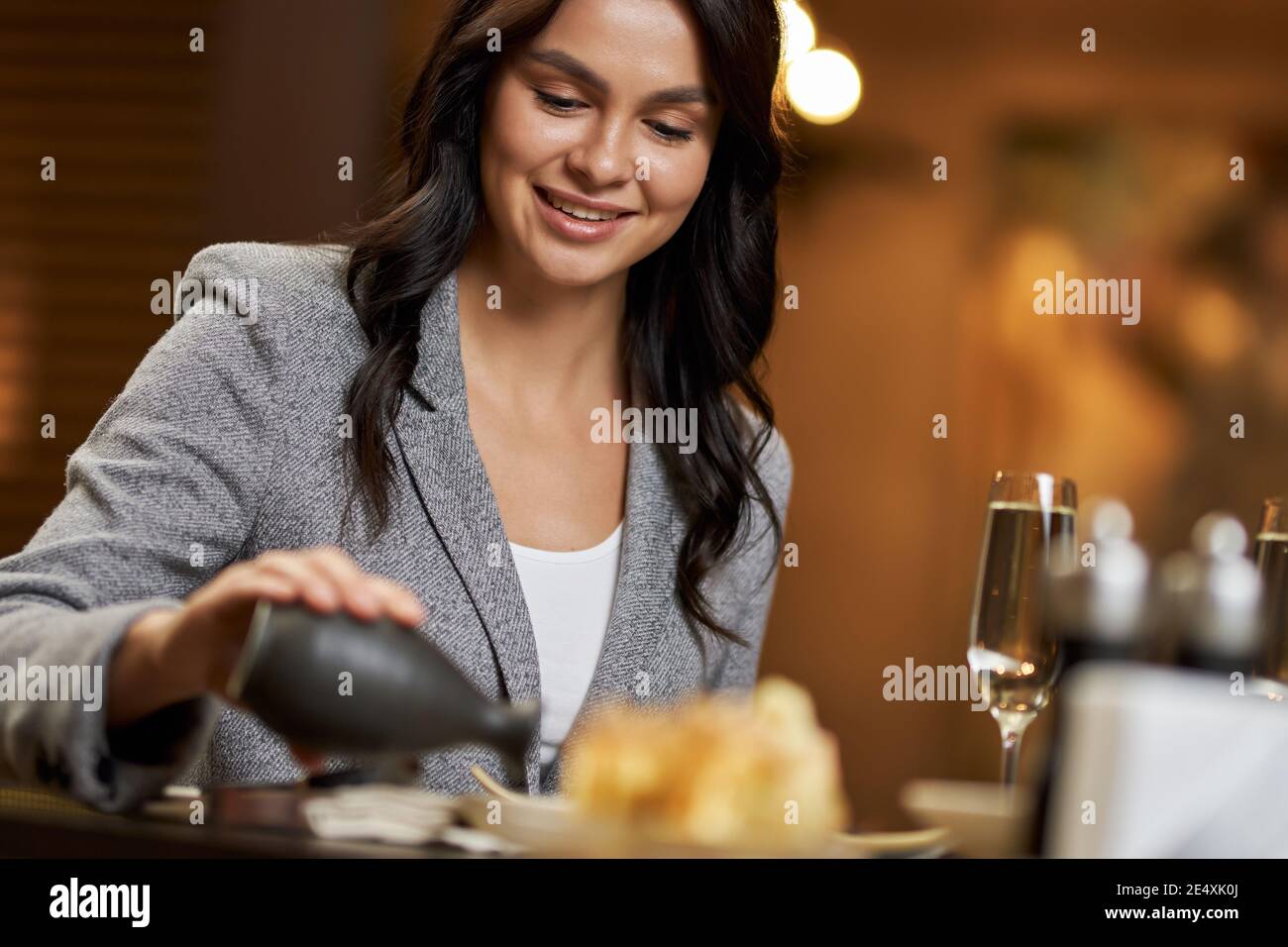 Bella signora brunette che versa un po 'più salsa di soia su di lei piatto con sushi Foto Stock