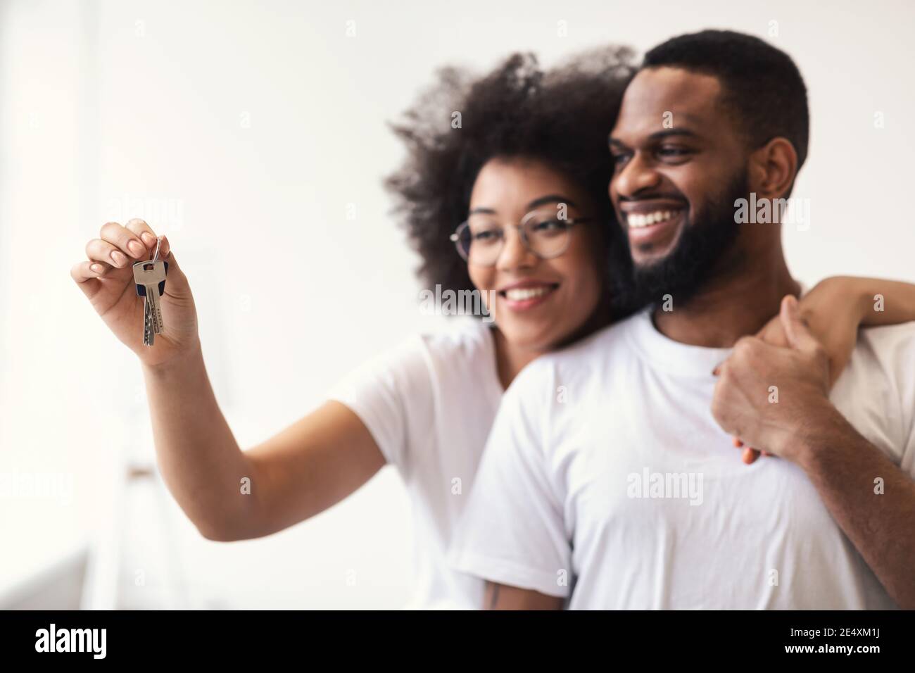 Happy African Couple Holding New House Key hugging Standing Indoor Foto Stock