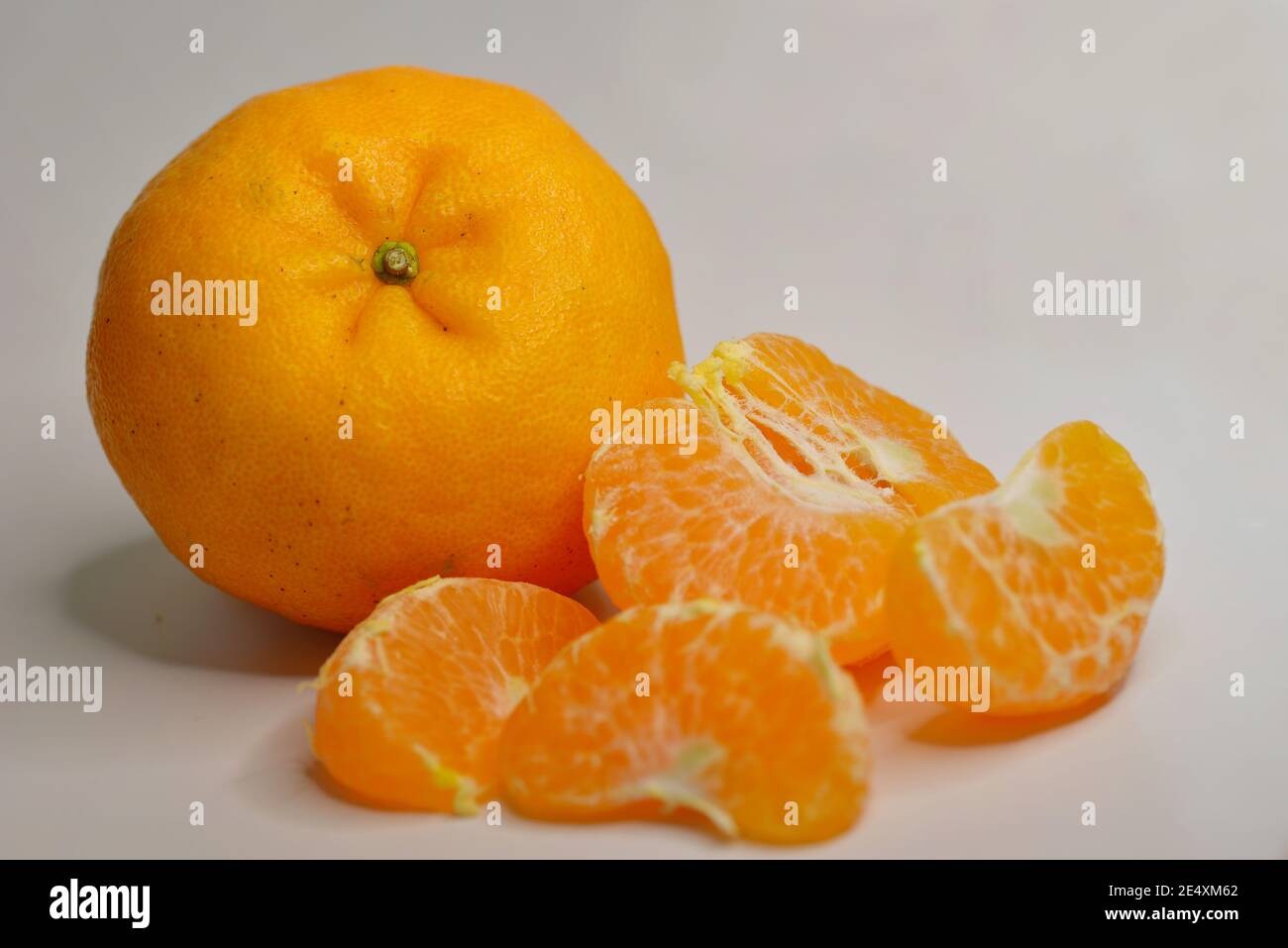 Primo piano di arance mandarine (Lukan) e segmenti sbucciati su bianco sfondo Foto Stock